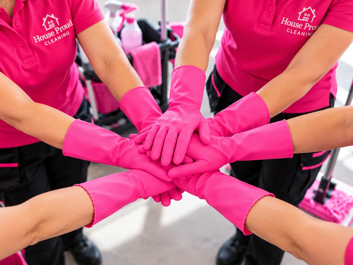 Pink rubber-gloved hands coming together in a team huddle